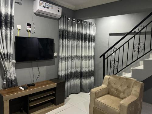 a living room with a chair and a flat screen tv at E&V APARTMENT Berger Express in Iseri-Oke