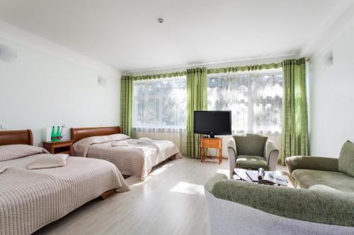 a bedroom with two beds and a tv and a couch at Mineraliniai Apartamentai in Druskininkai