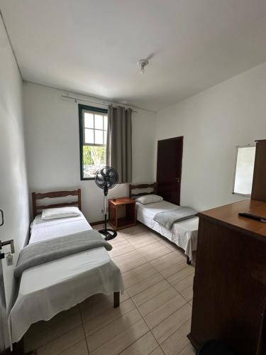 Habitación con 2 camas, escritorio y ventana. en POUSO CENTRO - Pouso dos Viajantes Unidade Centro OuroPreto, en Ouro Preto