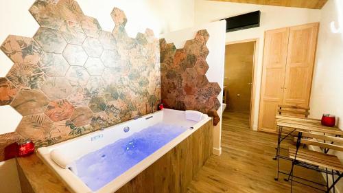 een groot bad in een kamer met een muur bij LE COTTAGE DU PARC in Chambéon