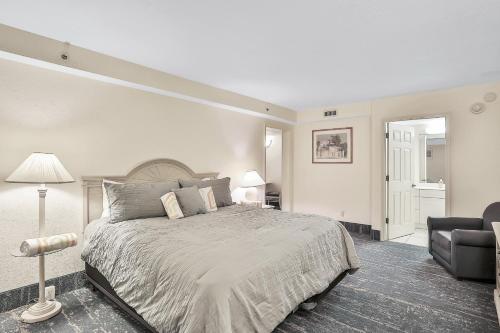 a white bedroom with a bed and a chair at Daytona Beach Resort 532-White Turtle in Daytona Beach