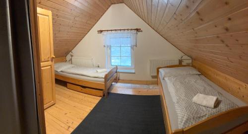 カールスボリにあるChata Eliškaのベッド2台と窓が備わる屋根裏部屋です。