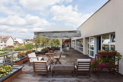 a deck with chairs and an umbrella on a building at Mineraliniai Apartamentai in Druskininkai
