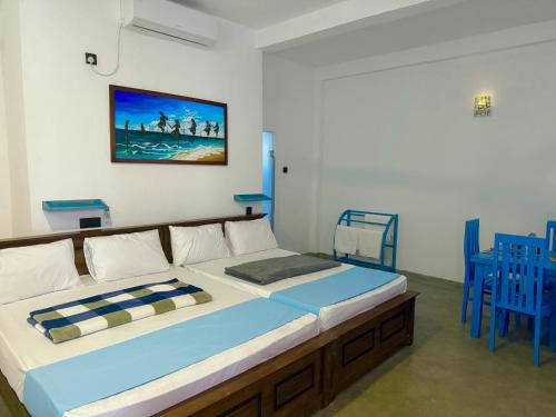 ein großes Bett in einem Zimmer mit blauen Stühlen in der Unterkunft The Lotus House - Ahangama in Ahangama