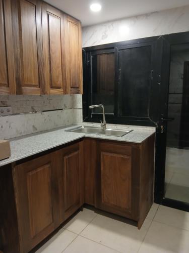 eine leere Küche mit einem Waschbecken und Holzschränken in der Unterkunft Residence Helice in Kinshasa