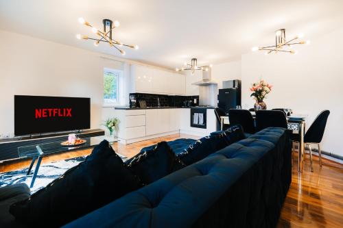 a living room with a blue couch and a kitchen at LUX 2BDR Flat in Woolwich I 2 Stops to Canary Wharf & Excel I Free Parking in Woolwich