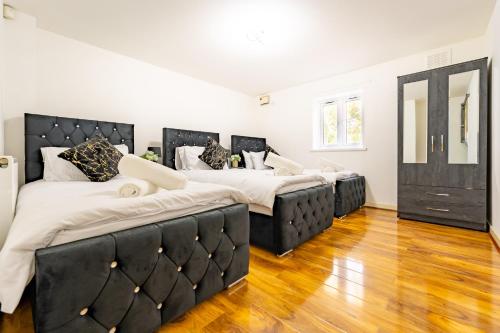 two beds in a room with wooden floors at LUX 2BDR Flat in Woolwich I 2 Stops to Canary Wharf & Excel I Free Parking in Woolwich