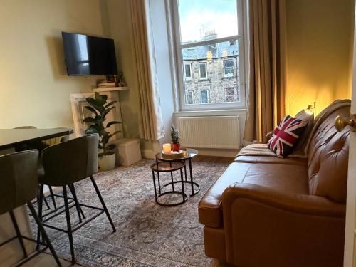 a living room with a couch and a table and a window at Murrayfield Spacious 2-bedroom apartment in Edinburgh