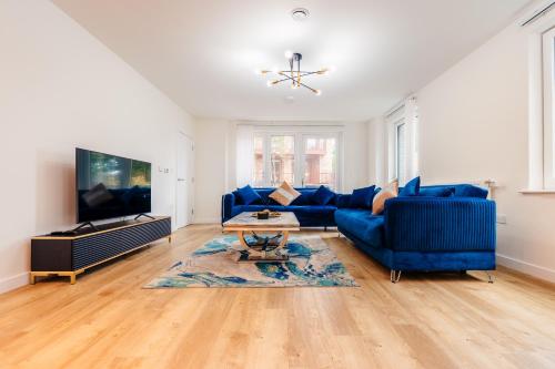 a living room with a blue couch and a tv at LUX 3BDR Riverside Duplex Mansionette By LCY & ExCeL I 20mins to Central London in London