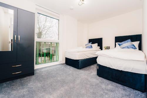 two beds in a room with two windows at LUX 3BDR Riverside Duplex Mansionette By LCY & ExCeL I 20mins to Central London in London