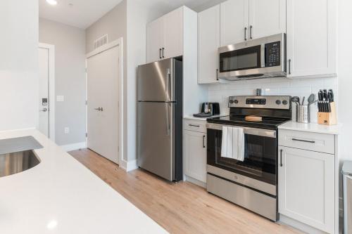 a kitchen with stainless steel appliances and white cabinets at Lux Studio Apt - Rooftop - 5 mins to The Fillmore in Philadelphia