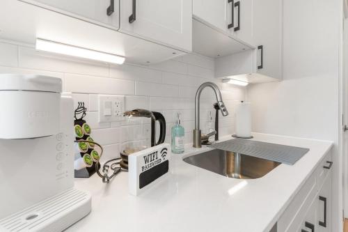 a white kitchen with a sink and a counter top at Lux Studio Apt - Rooftop - 5 mins to The Fillmore in Philadelphia