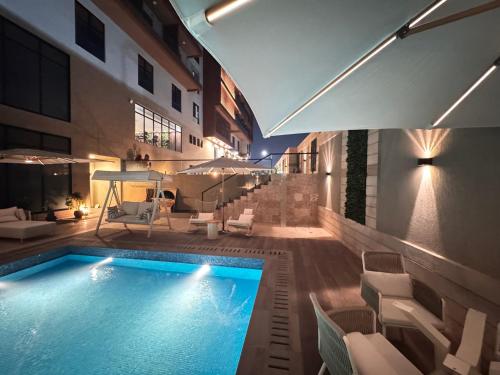 ein Pool mit weißen Stühlen und ein Gebäude in der Unterkunft The Grand Harmonia in Trofwi