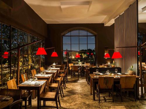 a restaurant with wooden tables and chairs and red lamps at Santa Teresa Hotel Rio de Janeiro - MGallery Collection in Rio de Janeiro