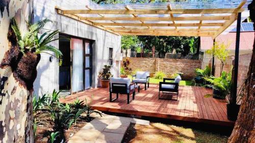 een houten terras met stoelen en een houten pergola bij Place on Oak 4 in Bulawayo