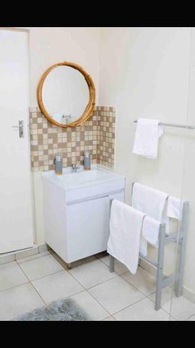 a bathroom with a sink and a mirror and a chair at Place on Oak 4 in Bulawayo