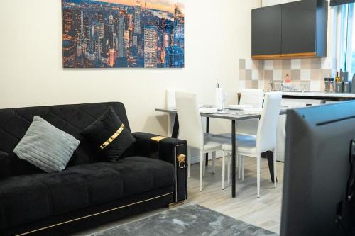 a living room with a black couch and a table at Cosy 2 BR Apt, DLR, London City Airport & ExCeL in London