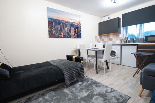 a living room with a black bed and a kitchen at Cosy 2 BR Apt, DLR, London City Airport & ExCeL in London