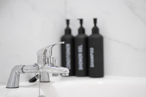 a bathroom sink with three bottles of wine at Cosy 2 BR Apt, DLR, London City Airport & ExCeL in London