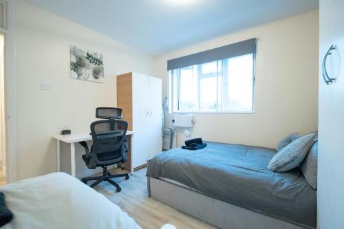 a bedroom with a bed and a desk and a chair at Cosy 2 BR Apt, DLR, London City Airport & ExCeL in London