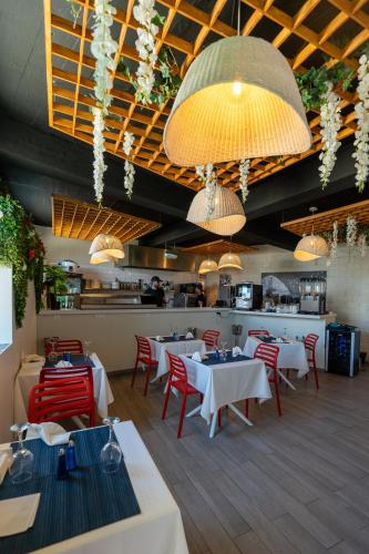 a restaurant with white tables and red chairs and lights at Mediterrâneo Madeira in São Vicente