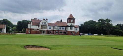 a large building with a clock tower on a golf course at Sarah's Woodland Golf Stays in Waterloo