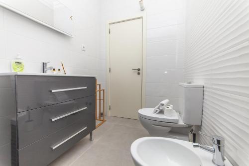 a white bathroom with a toilet and a sink at C09 - Portimão 3 Bed Holiday Apartment in Portimão