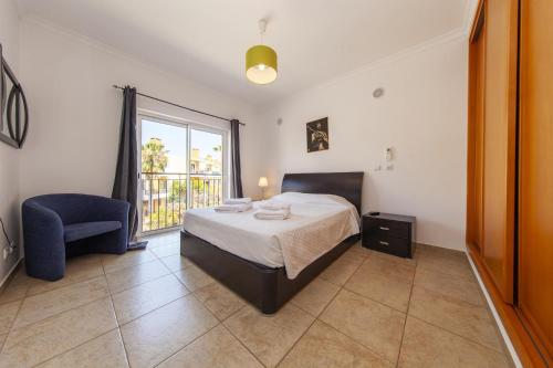 a bedroom with a bed and a chair and a window at C02 - Luxury 3 Bed With Pool View in Lagos
