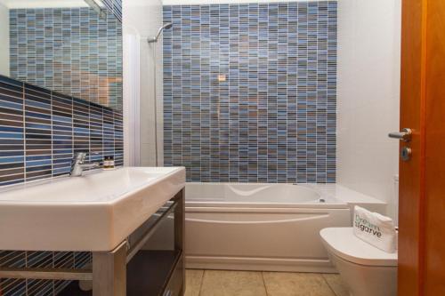 a bathroom with a sink and a tub and a toilet at C02 - Luxury 3 Bed With Pool View in Lagos