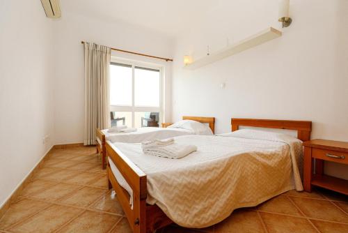 two beds in a room with a window at C03 - Galé Holiday Apartment in Lagos in Lagos
