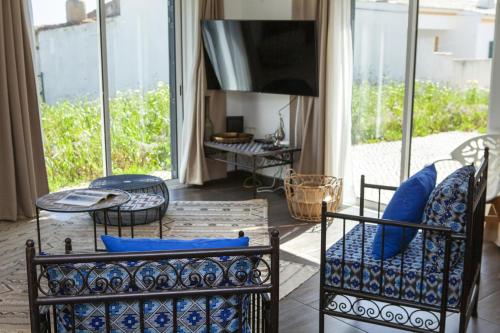 a living room with a couch and chairs and a tv at D13 - Eiras Velhas Holiday House in Almádena in Almádena