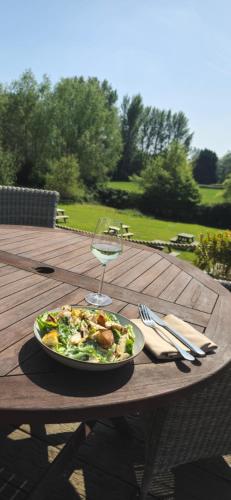 Un plato de ensalada y una copa de vino en una mesa de madera. en The Carpenters Arms, en Newbury