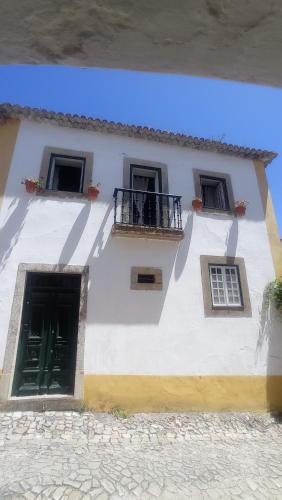 a white building with three windows and a balcony at Casa das Glicínias in Óbidos