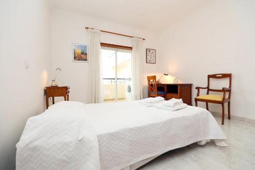 a white bedroom with a white bed and a chair at C19 - Do Mar Apartment in Lagos in Lagos