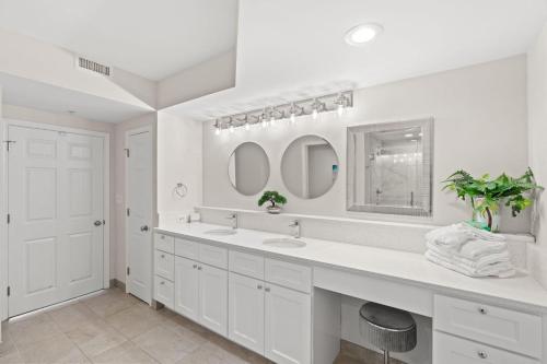 a white bathroom with two sinks and two mirrors at Barefoot Resort - North Tower 905 - Windy Hill in Myrtle Beach