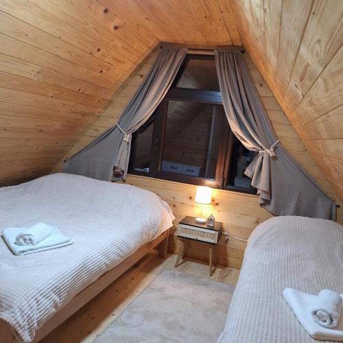 an attic bedroom with two beds and a window at Brvnara Gorska Dama in Sekulić 