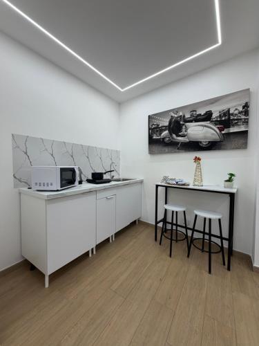 una cucina con ripiani bianchi, un tavolo e un microonde di Maison Ferba a Palermo