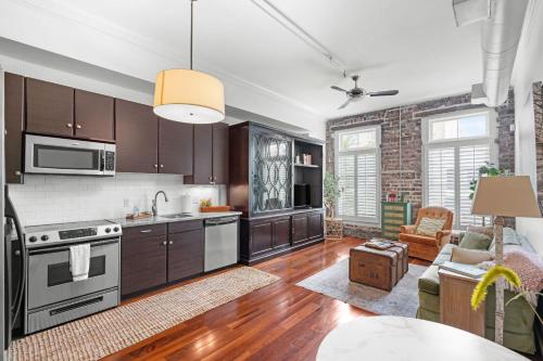 a kitchen with wooden cabinets and a living room at Knockout Loft- Near Plant Riverside in Savannah