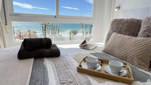a room with a bed with a tray with two coffee cups at Wake up to the Oceanfront Panoramic 180º Beachview Torrox-Costa Ruselo R408 ONLY ADULTS in Torrox Costa