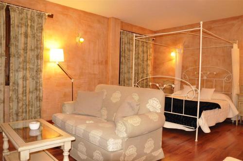 a living room with a couch and a bed at Hotel Rural Carlos I in Garganta la Olla