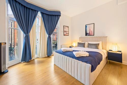 a bedroom with a large bed with blue drapes at Private Oxford Street Luxe Apartment in London