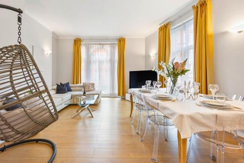 a living room with a long table with chairs at Private Oxford Street Luxe Apartment in London