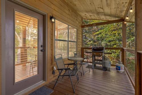 een afgeschermde veranda met een tafel en stoelen en een grill bij The Wild Life cabin in Hatchertown