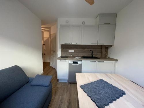 een woonkamer met een blauwe bank en een keuken bij Studio avec canapé lit 2 places dans pièce de vie et lit une place dans coin nuit in Saint-Mandrier-sur-Mer