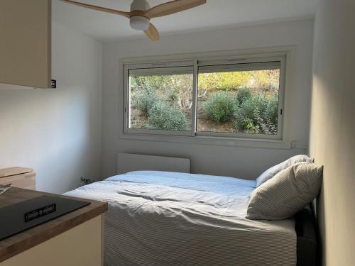 een slaapkamer met een bed voor een raam bij Studio avec canapé lit 2 places dans pièce de vie et lit une place dans coin nuit in Saint-Mandrier-sur-Mer