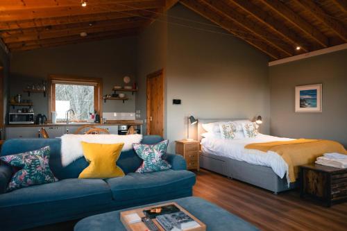 a living room with a bed and a blue couch at The Bothy at Coneloch in Elgin