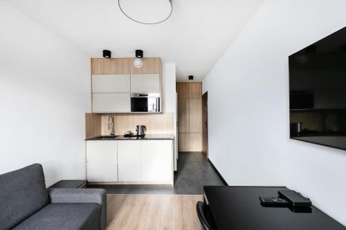 Una sala de estar con un sofá y una cocina. en Apartamenty Platinex 1, en Cracovia