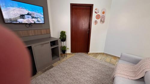 a living room with a flat screen tv on a wall at Pousada Vivenza in Laguna