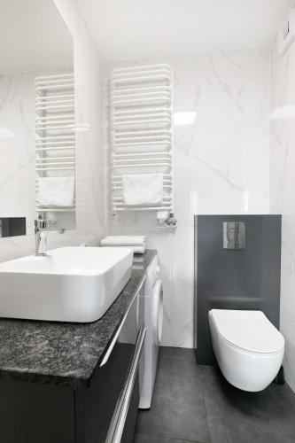 a white bathroom with a sink and a toilet at Apartamenty Platinex 1 in Krakow
