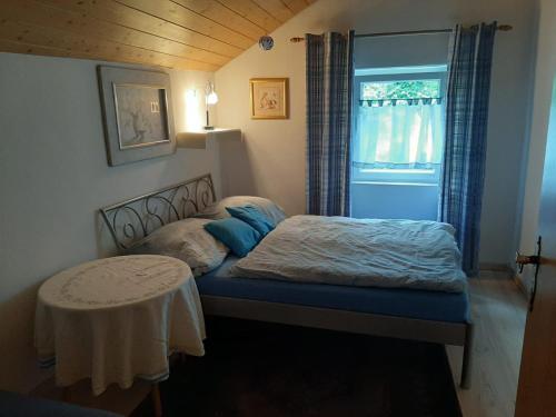 een slaapkamer met een bed met een tafel en een raam bij Ferienhaus Landau in Landau an der Isar